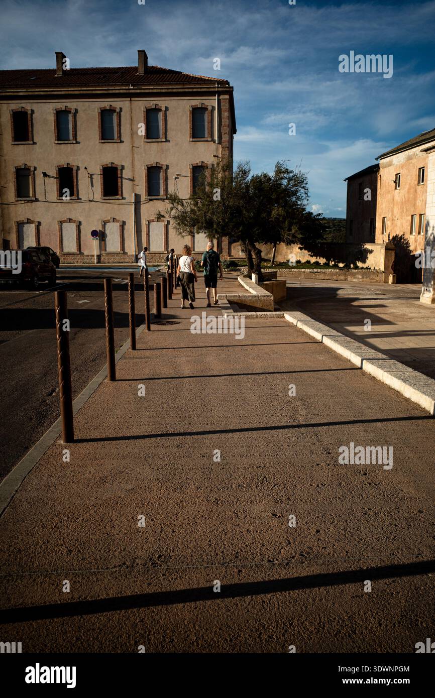 Menschen, die in Bonifacio, Korsika, Frankreich, in einer sonnendurchfluteten Straße spazieren gehen. Stockfoto