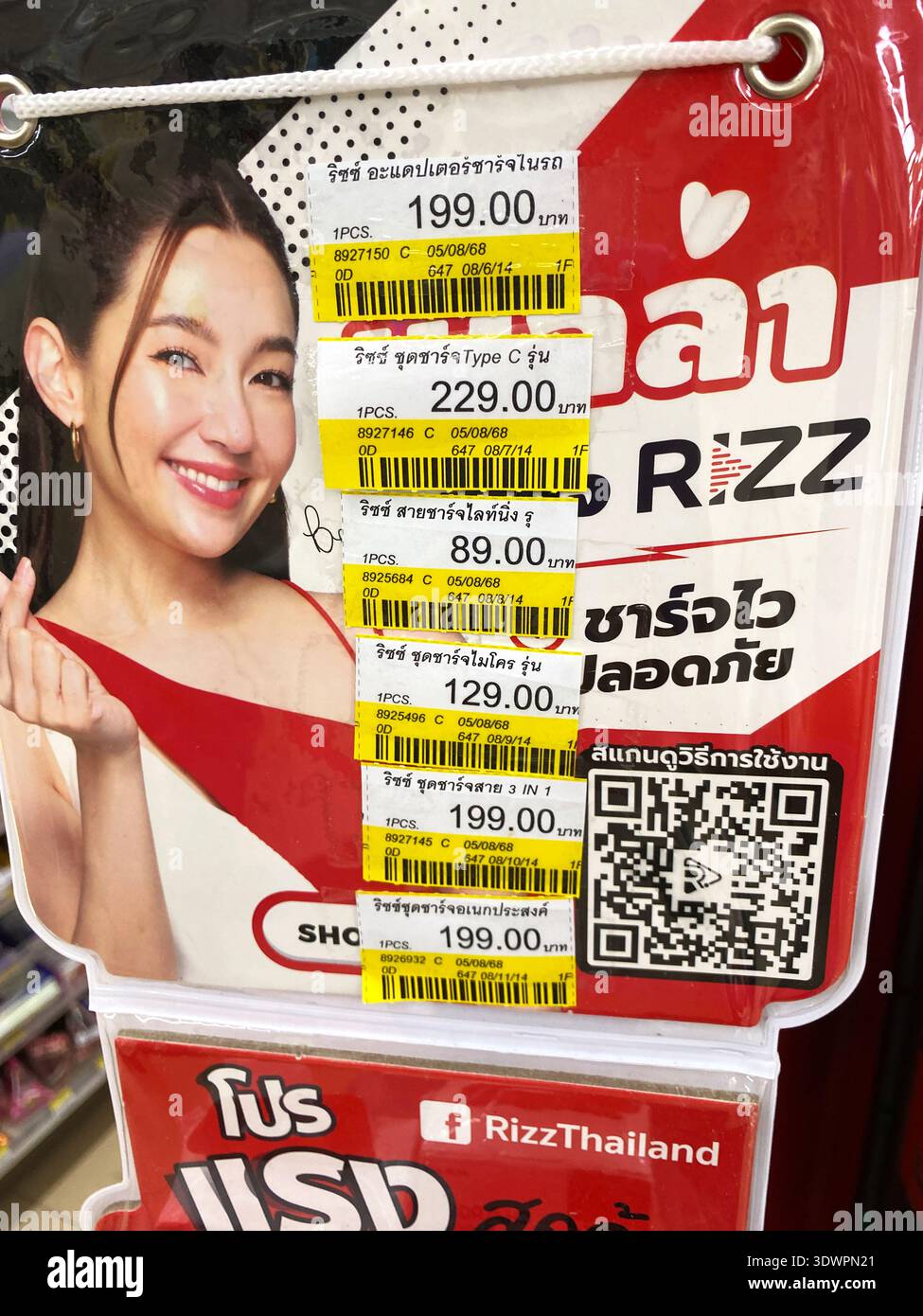 Phuket, Thailand - 27. Oktober 2025: Werbeausstellung in einem thailändischen Geschäft mit Preisschildern und einer lächelnden Frau in einem roten Kleid, die für Rizz Producc wirbt Stockfoto