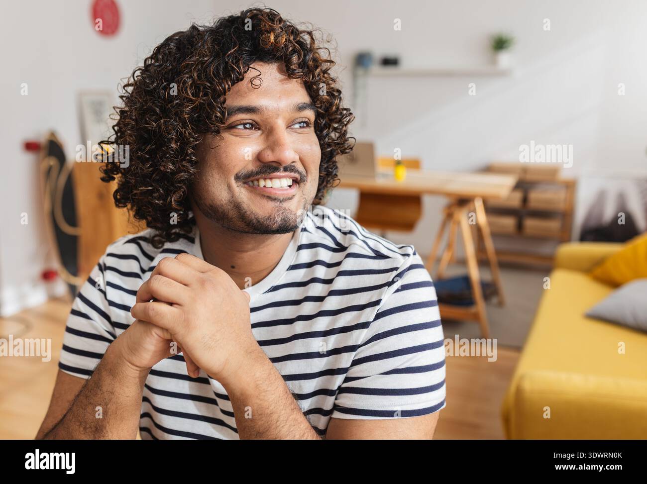 Junger Indianer, der wegschaut und am Schreibtisch lächelt Stockfoto
