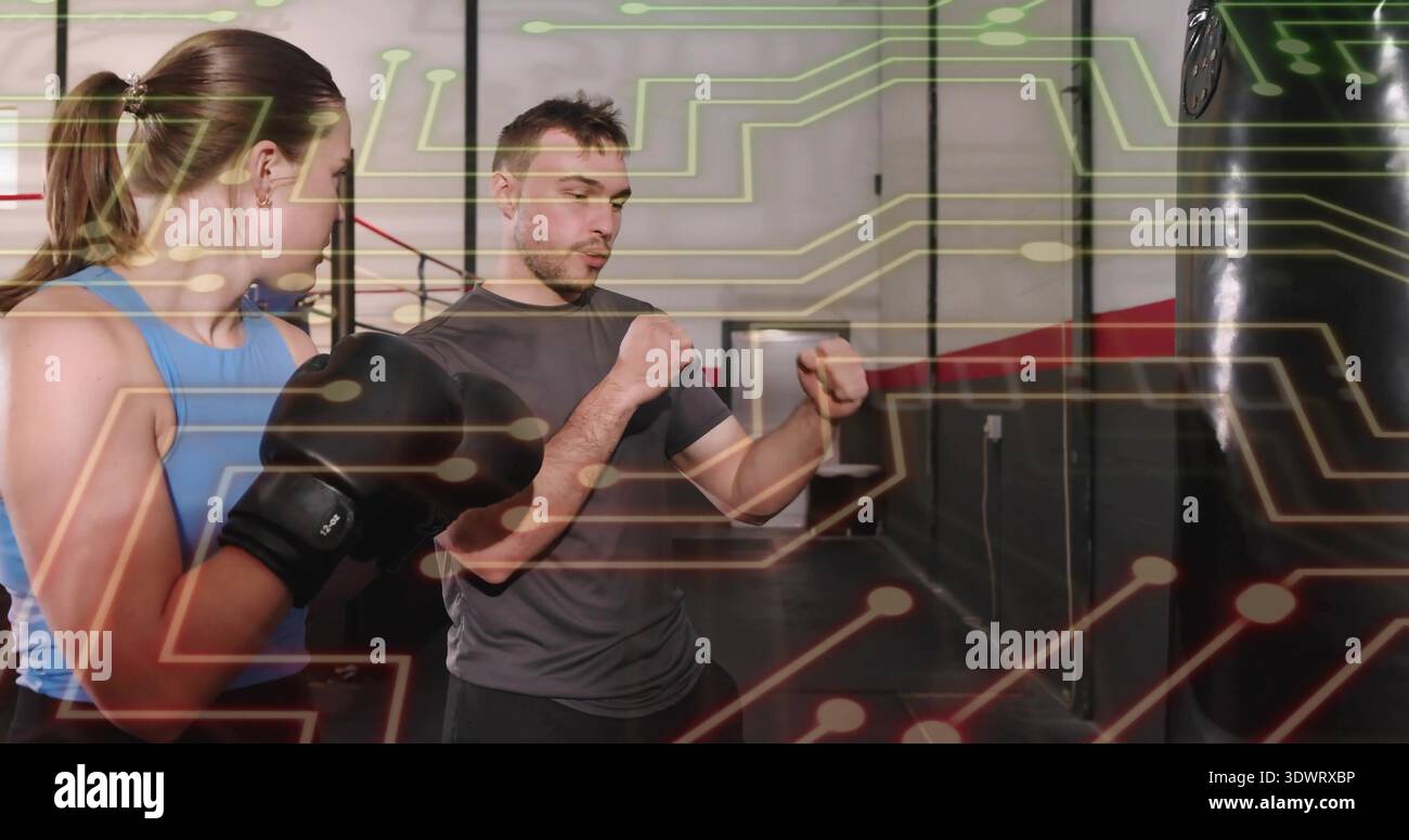 Trainertrainer, der den Trainee beim Boxen anleitet, blauer Tank, schwarze Handschuhe, Circuit-Overlay Stockfoto