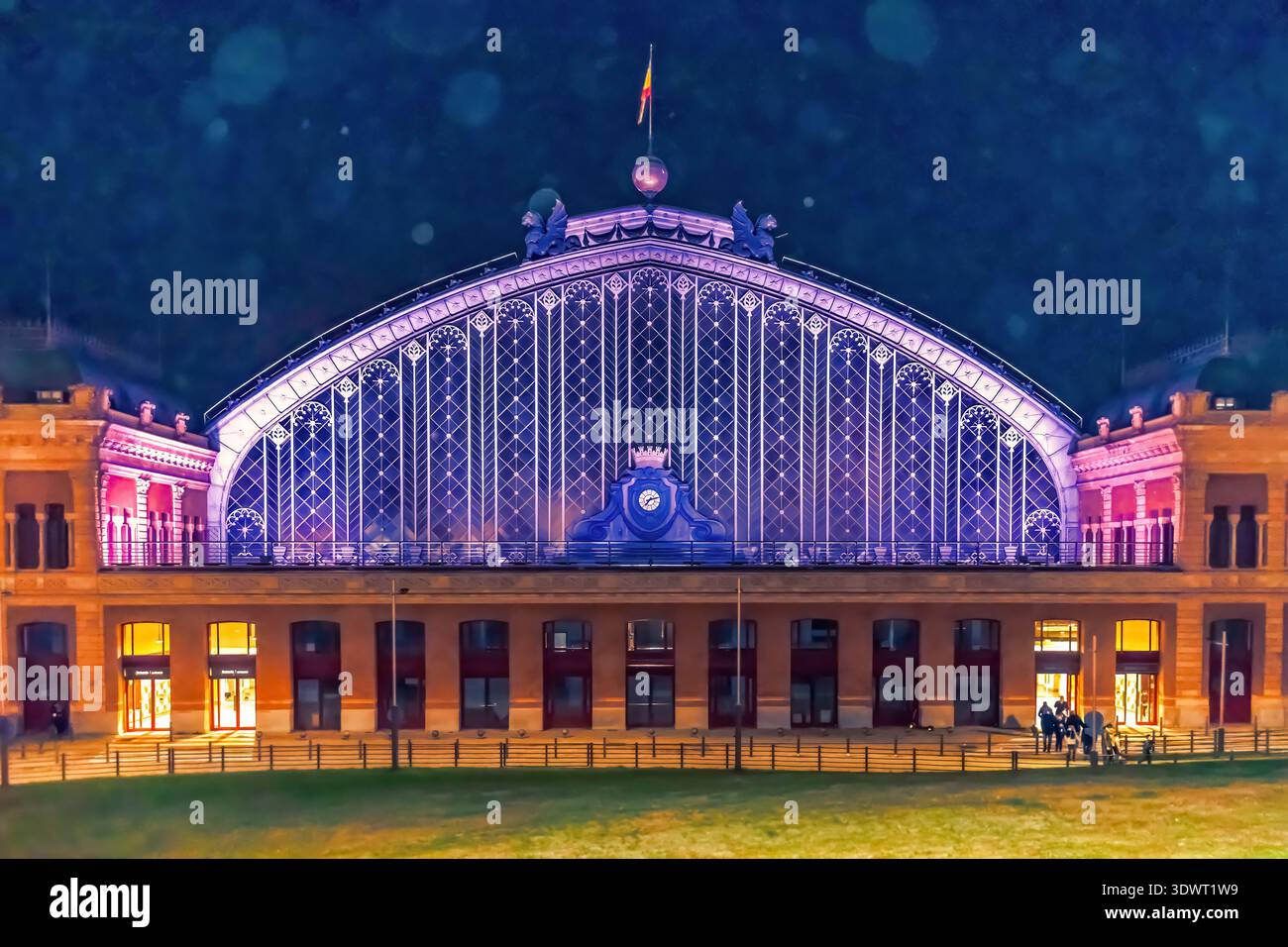 Der Bahnhof Atocha in Madrid ist bei Nacht beleuchtet und hat eine lebhafte Beleuchtung, die seine großen Bogenstrukturen hervorhebt. Madrid, Spanien - 30. November 2021 Stockfoto
