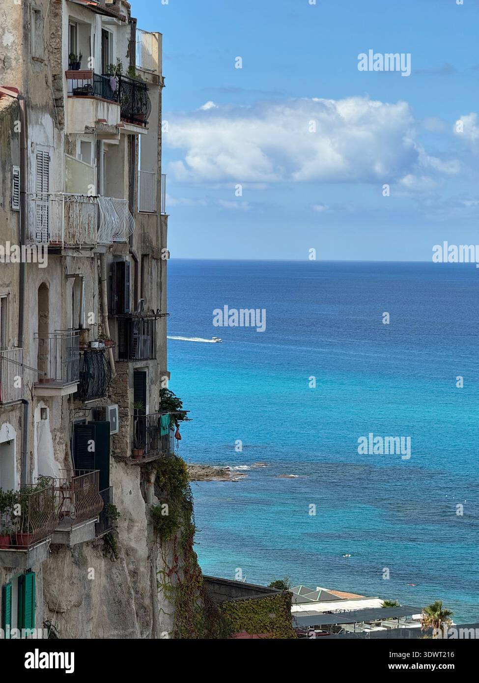 Häuser an den Klippen mit Blick auf das türkisfarbene Meer an der Küste von Tropea, Kalabrien, Italien, mit Balkonen zum Mittelmeer. - Smartphone-aufgenommenes Stockfoto