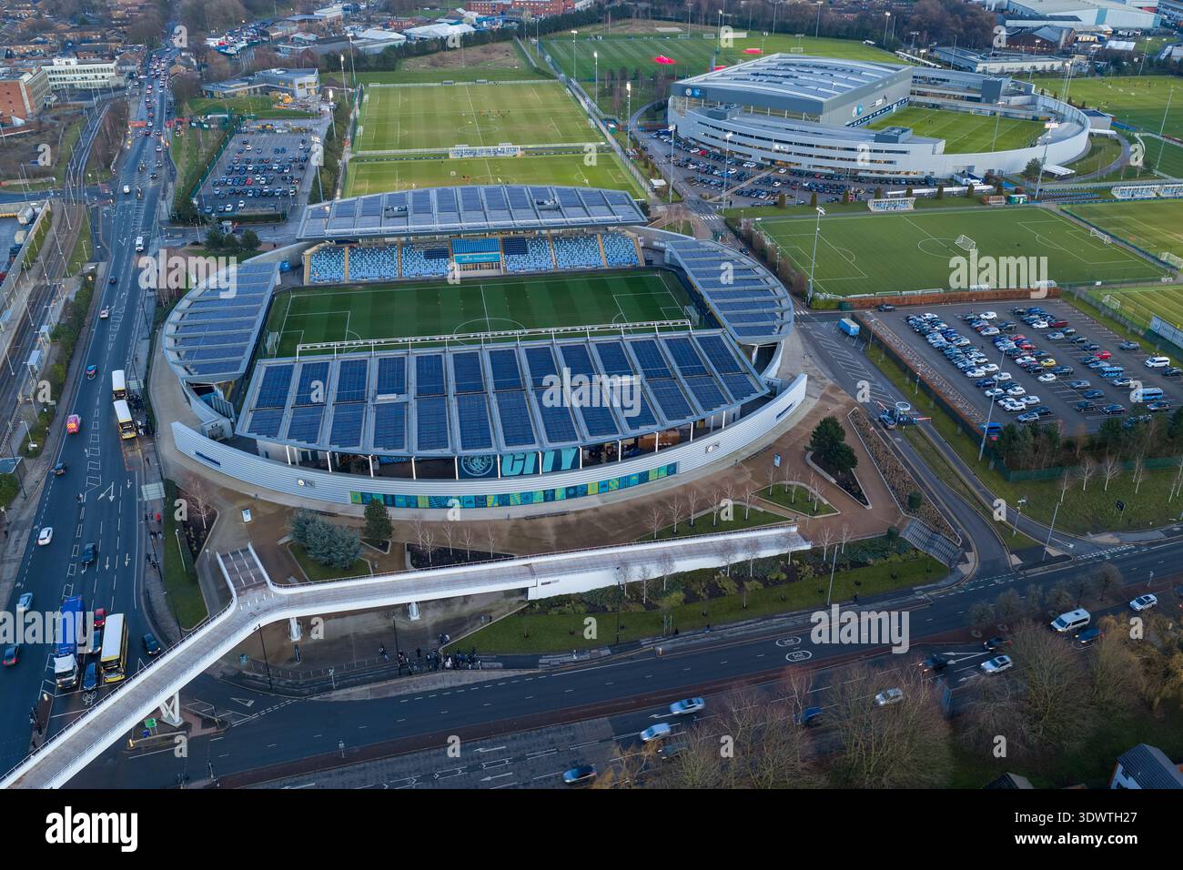 Luftbild des Etihad Campus in Manchester bei Sonnenuntergang mit dem Joie Stadium und der Fußgängerbrücke über den Alan Turing Way. Stockfoto
