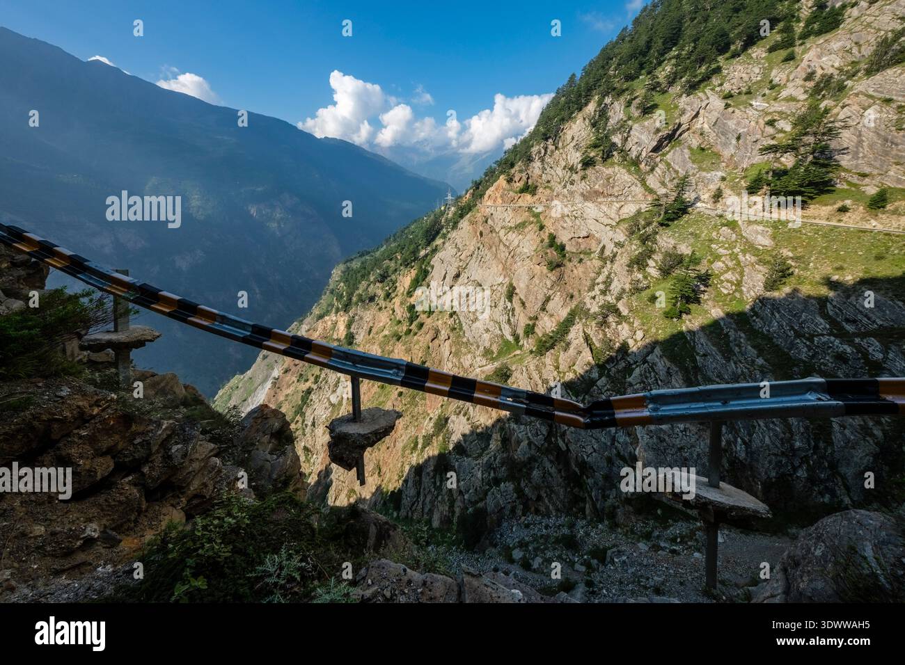 Eine beschädigte Absturzsperre hängt gefährlich über einer tiefen Schlucht am Suicide Point nahe Kalpa, mit der steilen Felswände des Berges in der Ferne. Stockfoto