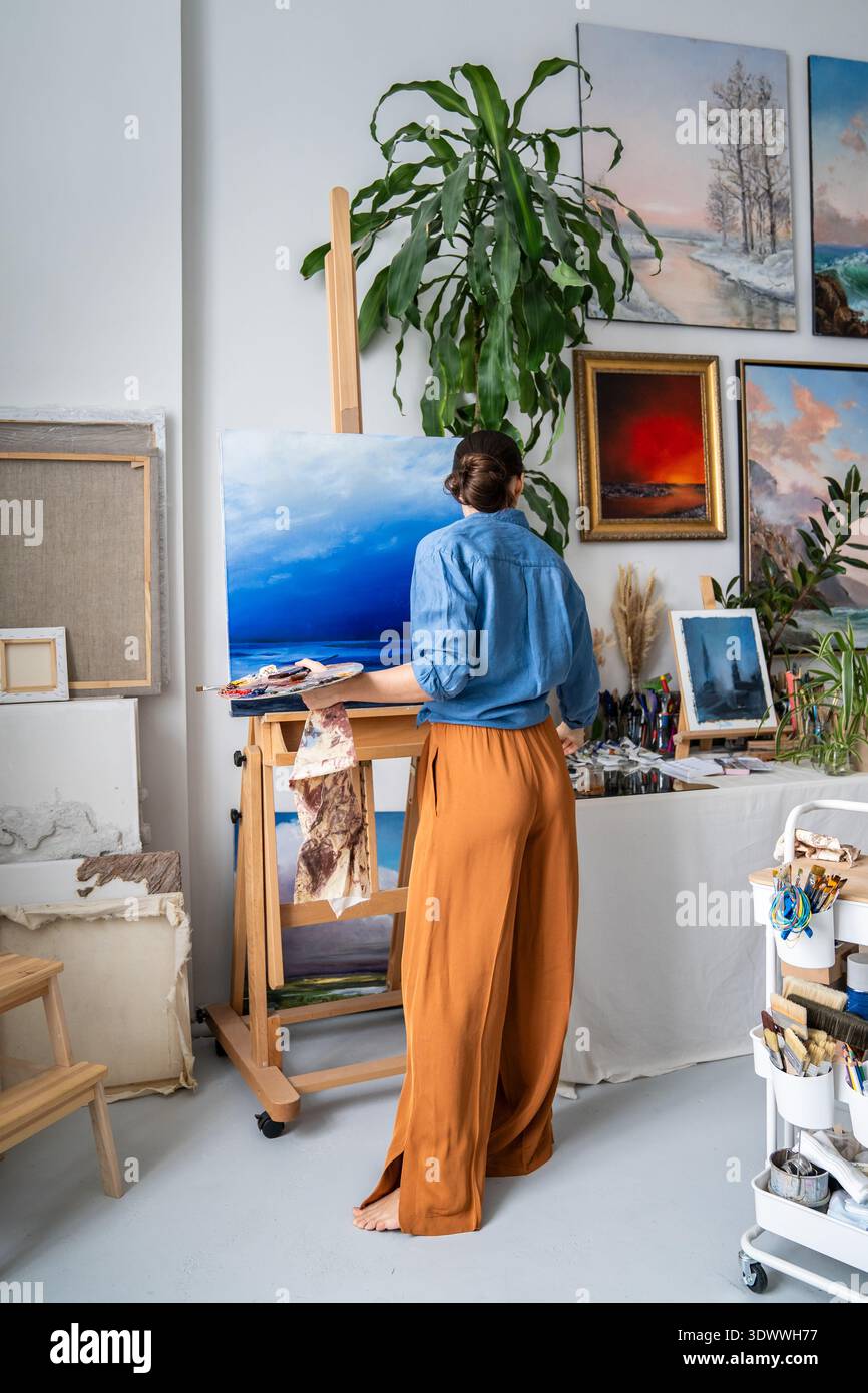 Inspirierte Künstlerin malte Landschaftsbilder auf Leinwand mit Ölfarben und genießt kreatives Hobby Stockfoto