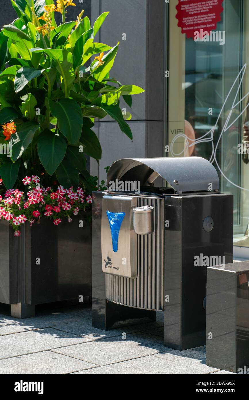 Moderner Abfallbehälter mit integriertem Hundeabfallsbeutel und Blumen, die den öffentlichen Service, das umweltfreundliche Design und den Stolz der Bürger hervorheben Stockfoto