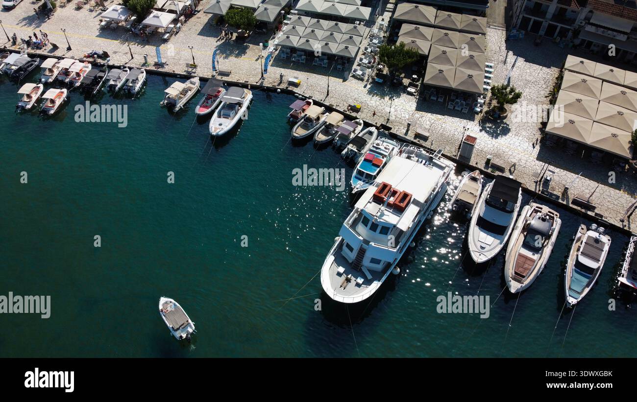 Aus der Vogelperspektive des Yachthafens von Sivota, Griechenland. Drohnenaufnahme von Touristen- und Fischerbooten, die am Steinpier mit klarem türkisfarbenem Ionischen Meerwasser vor Anker liegen. Stockfoto