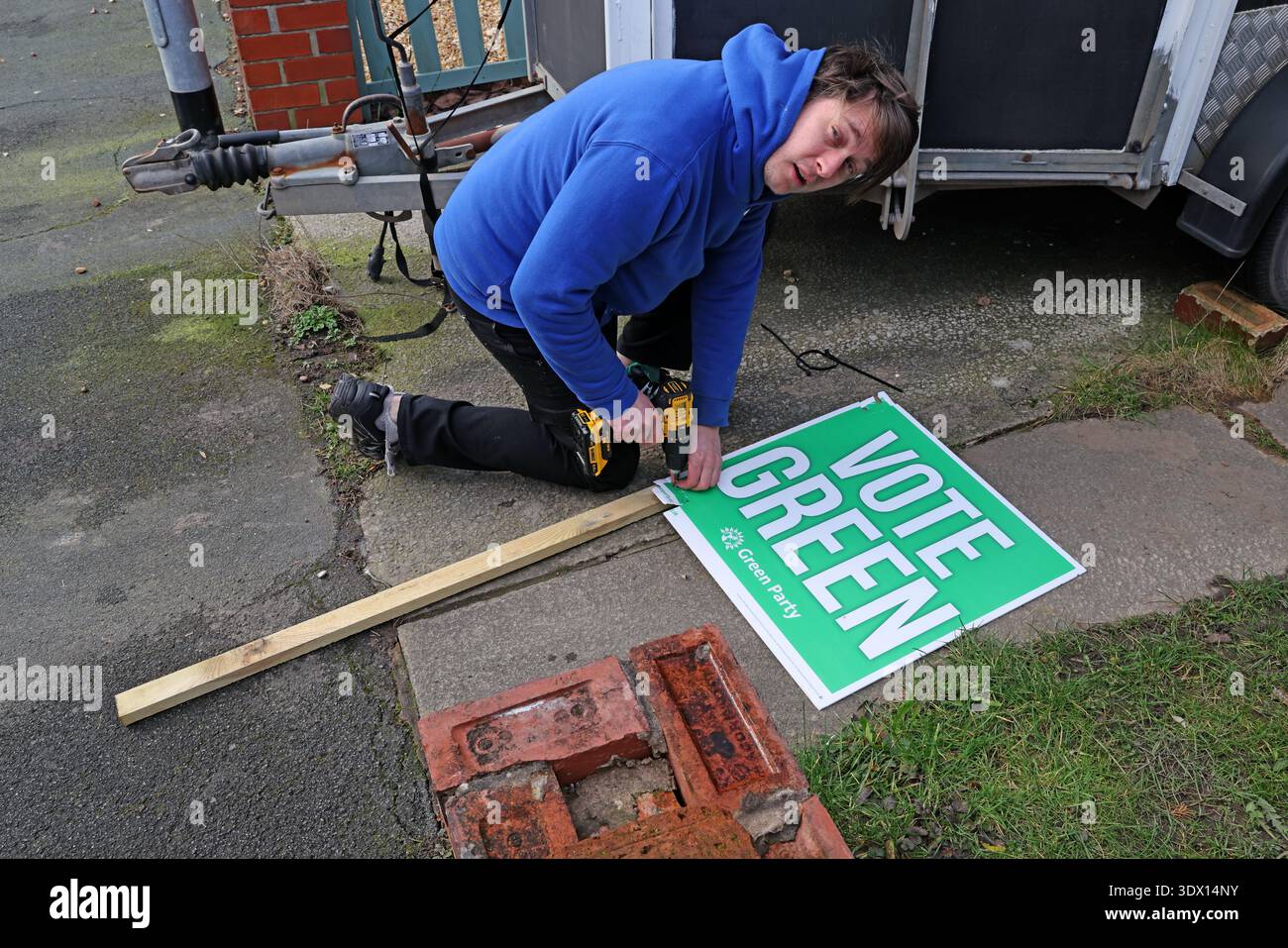Green Party Freiwillige installieren ein „Vote Green“ Gartenpfeilbrett vor dem Haus eines Unterstützers in Denton, Greater Manchester, England, Großbritannien. Stockfoto