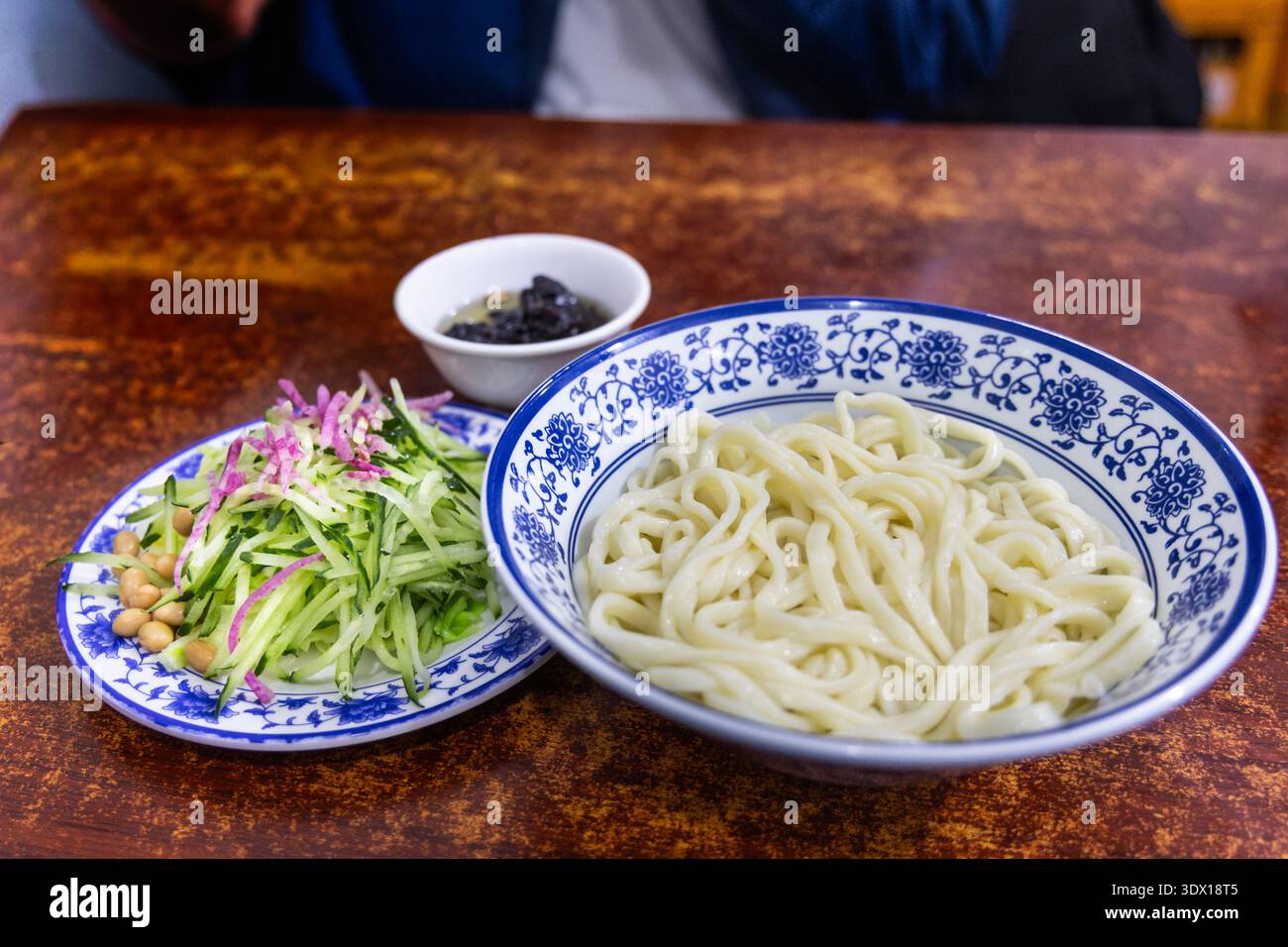 Eine ungemischte Portion des beliebten Zhajiangmian, Nudeln mit Garnitur und Paste im Restaurant. Stockfoto