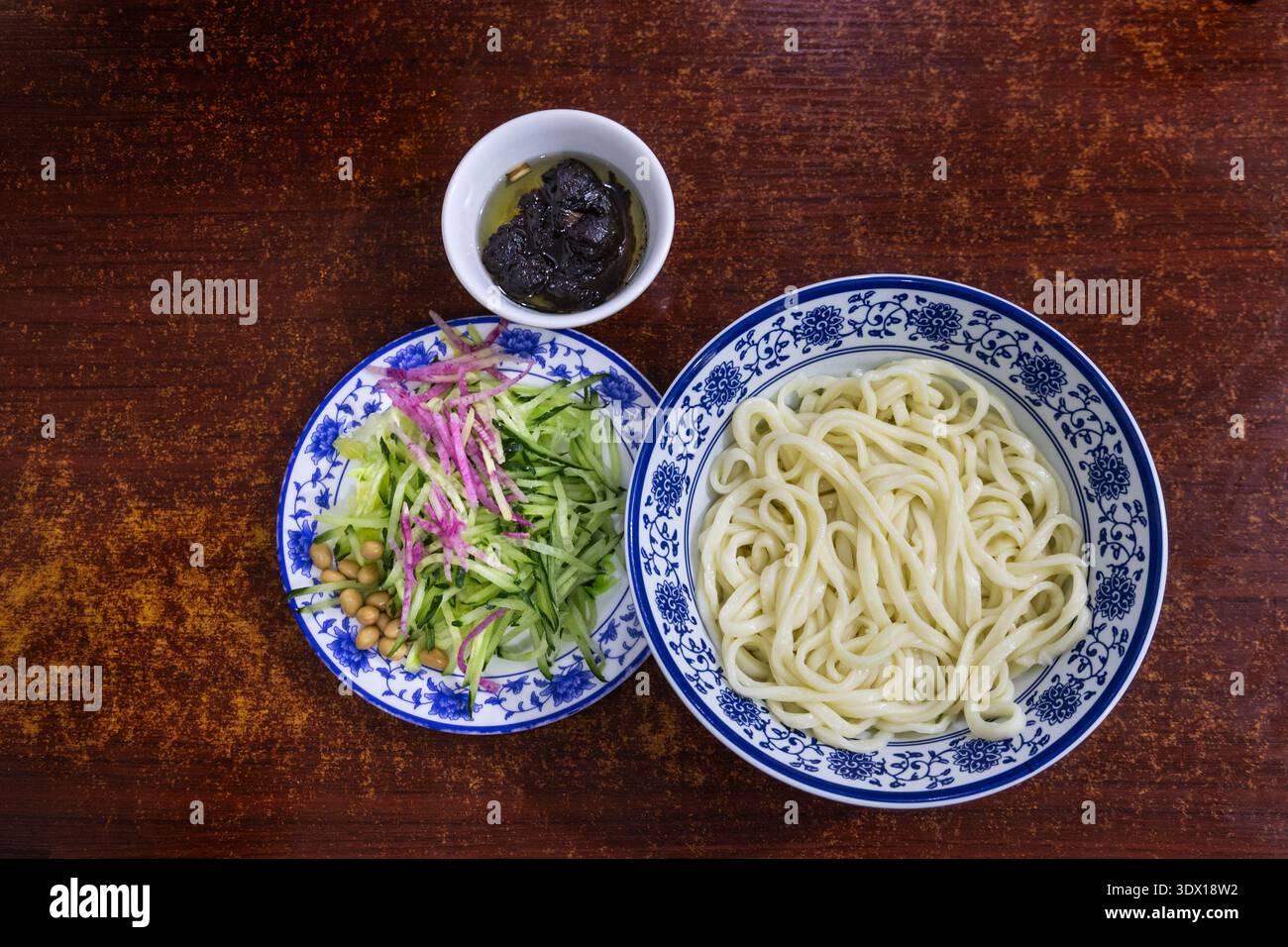 Blick von oben auf eine ungemischte Portion des beliebten Zhajiangmian, Nudeln mit Garnitur und Paste im Restaurant. Stockfoto