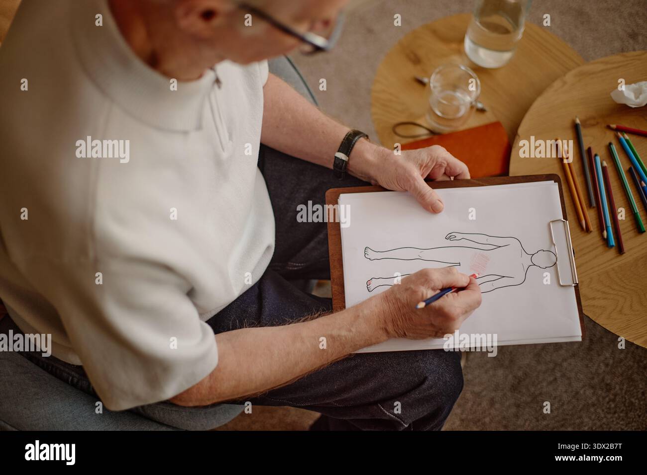 Senior Caucasian man zeichnet menschliches Körperdiagramm während der Psychologiesitzung Stockfoto