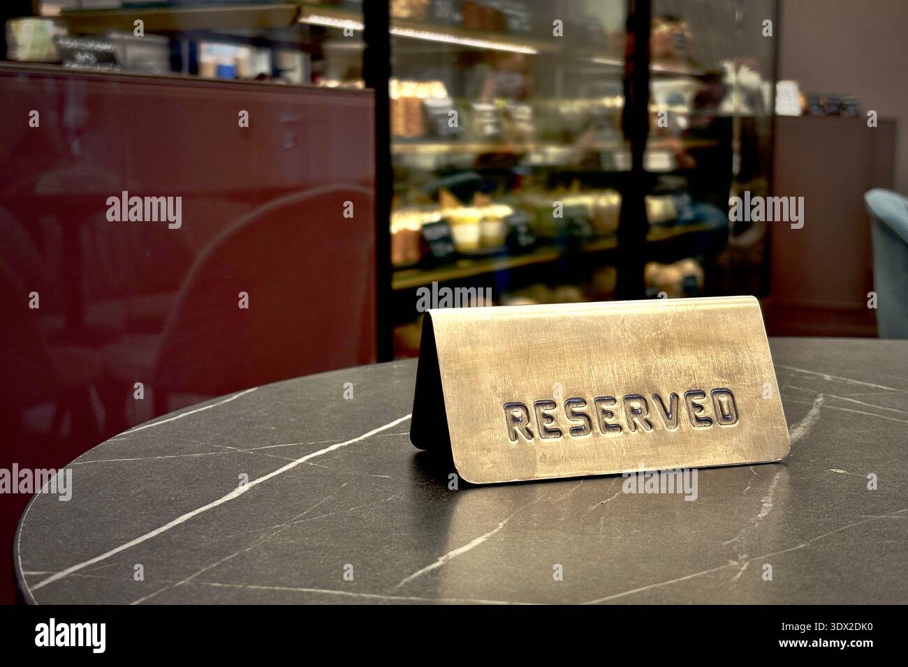 Ein reserviertes Schild in einem stilvollen, urbanen Café, Marmoroberfläche und Bokeh-Lichter sorgen für eine intime Atmosphäre beim Essen Stockfoto