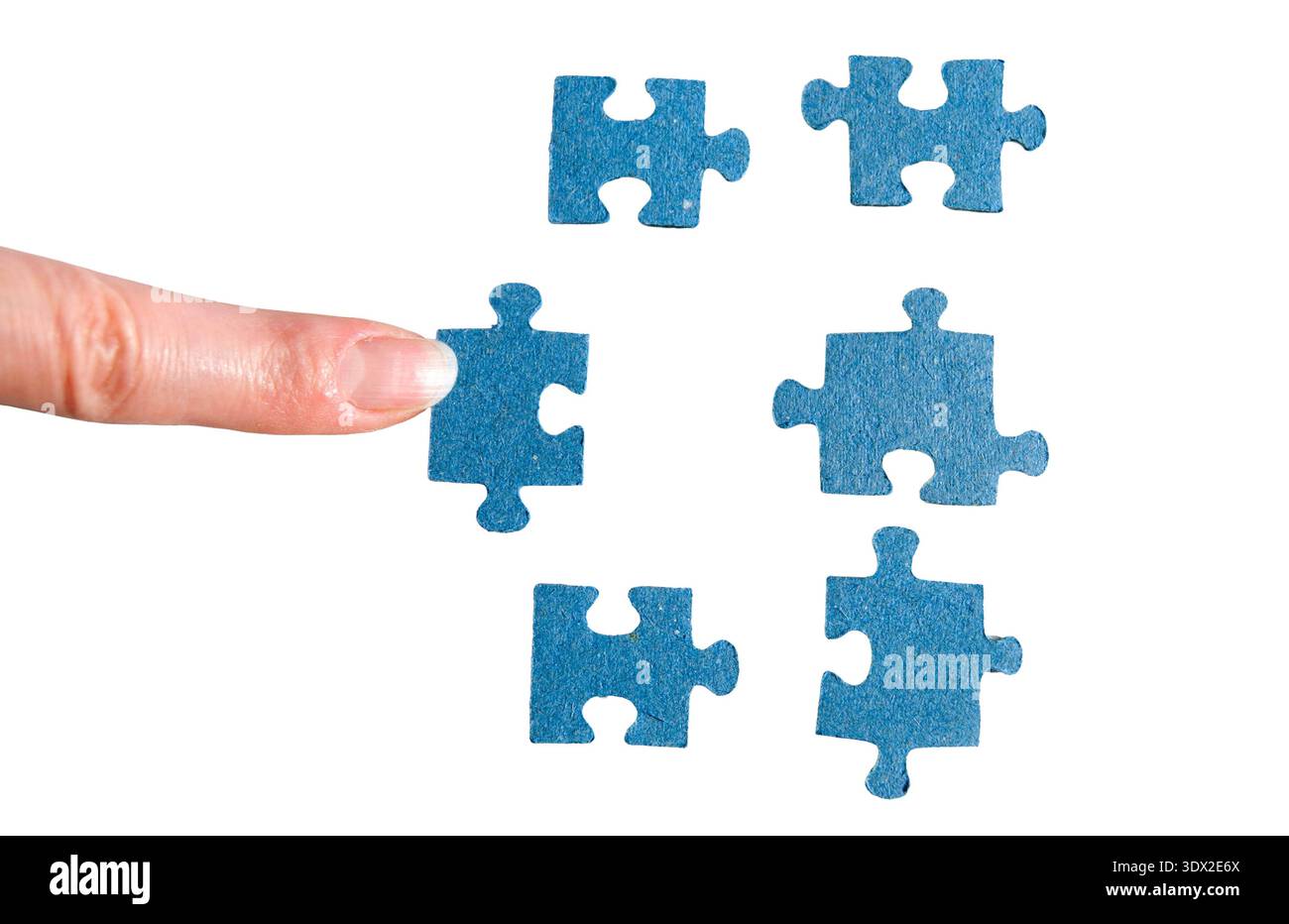 Ein Finger fügt ein blaues Stichsägestück hinzu. Eine Hand, die ein Puzzleteil hält. Stockfoto