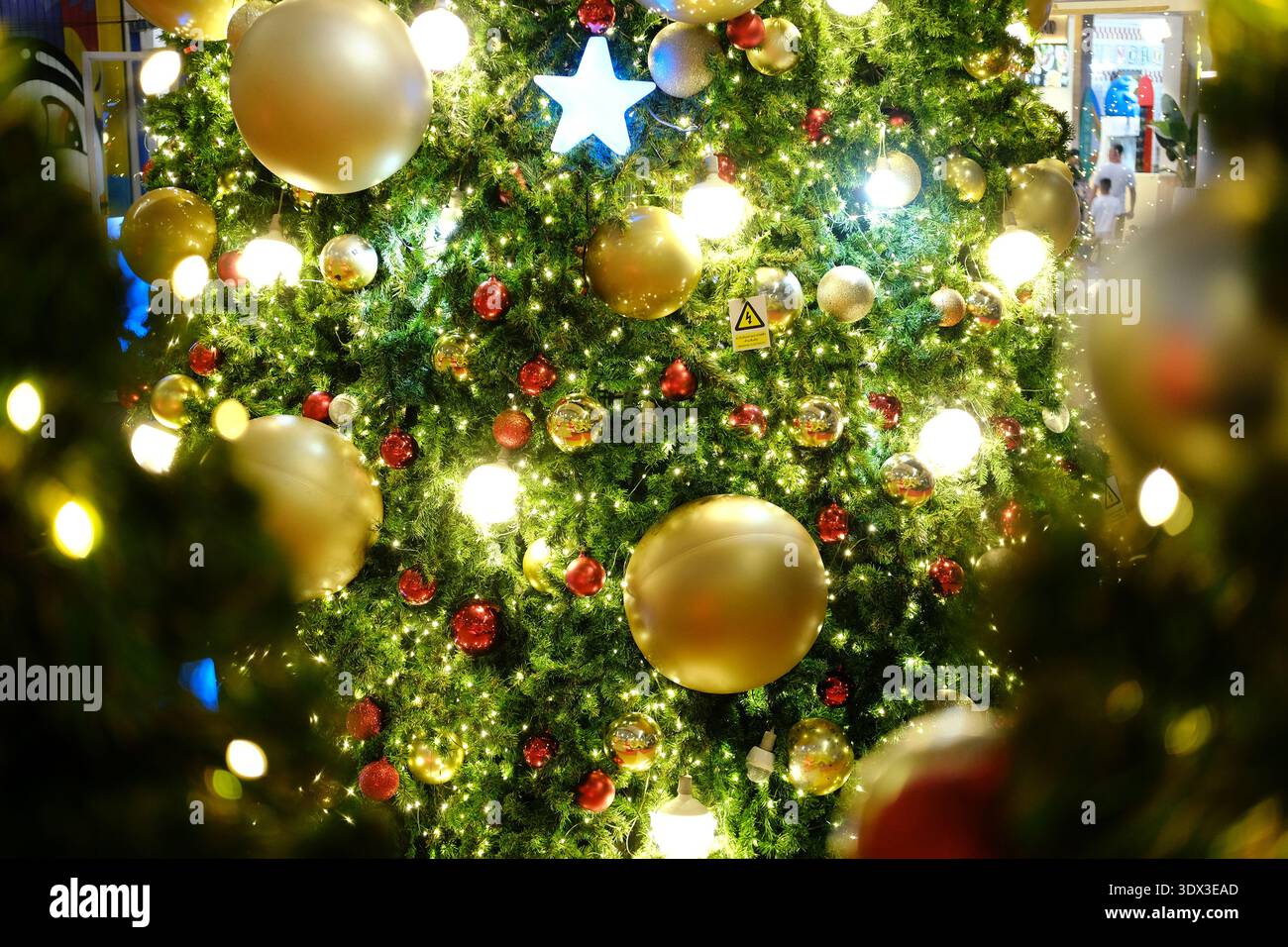 Der Weihnachtsbaum ist mit glitzernden Ornamenten und hellen Lichtern verziert und schafft eine festliche Umgebung voller Weihnachtsstimmung und Feierlichkeiten Stockfoto