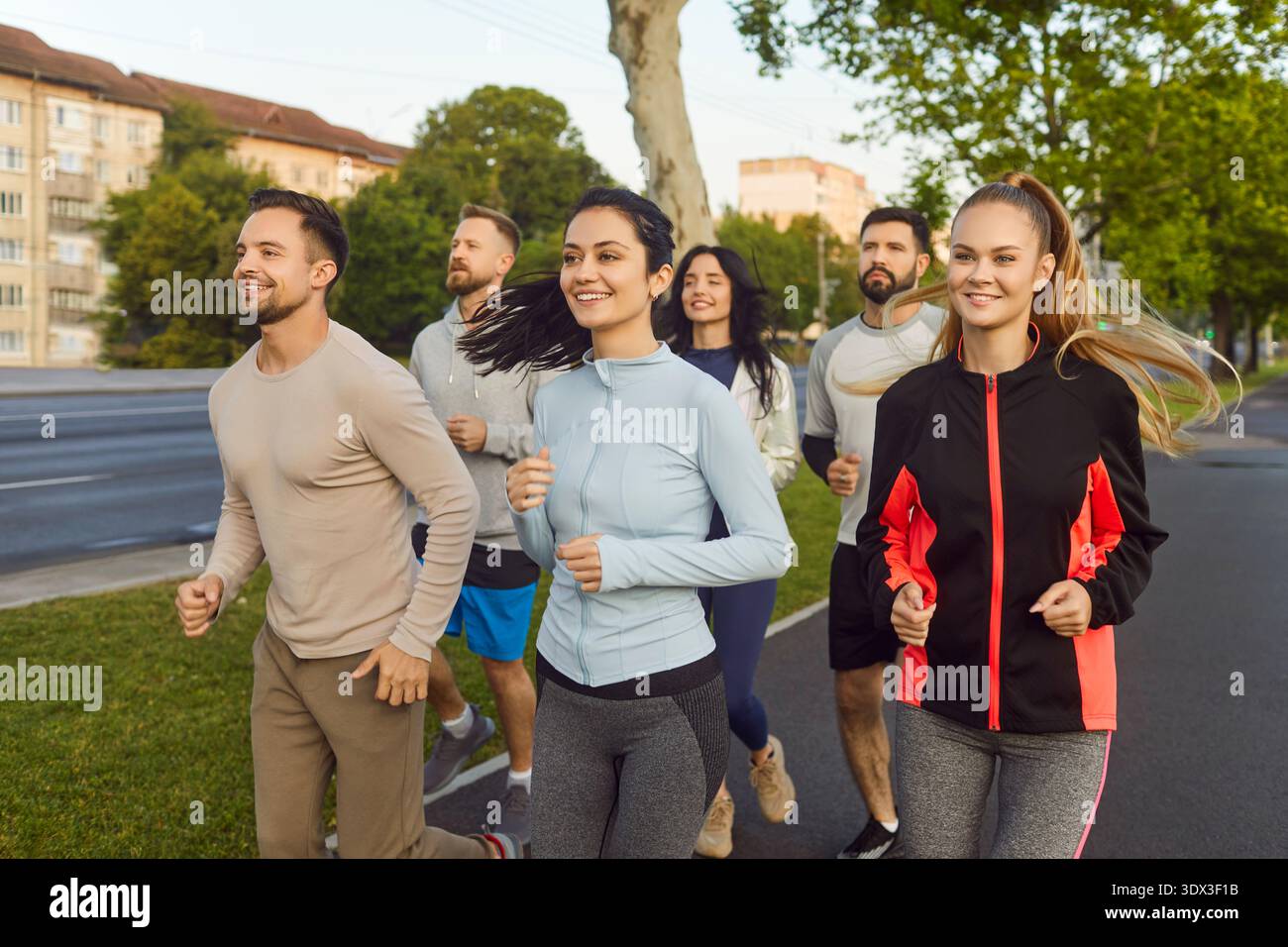 Gruppe von Läufern, die im Sommer im Stadtpark joggen, Team läuft entlang der Straße Stockfoto