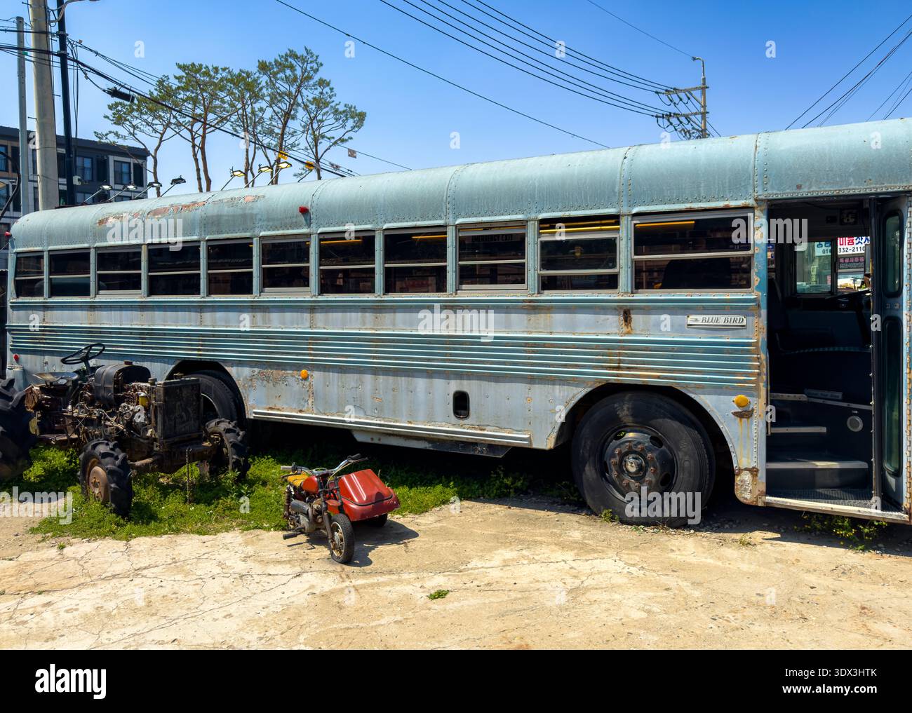 Verlassener Bus in einer ländlichen Umgebung unter strahlender Sonne, mit rostigem Metall und der stillen Nostalgie eines einst gebrauchten Fahrzeugs. - Smartphone-aufgenommenes Stockfoto