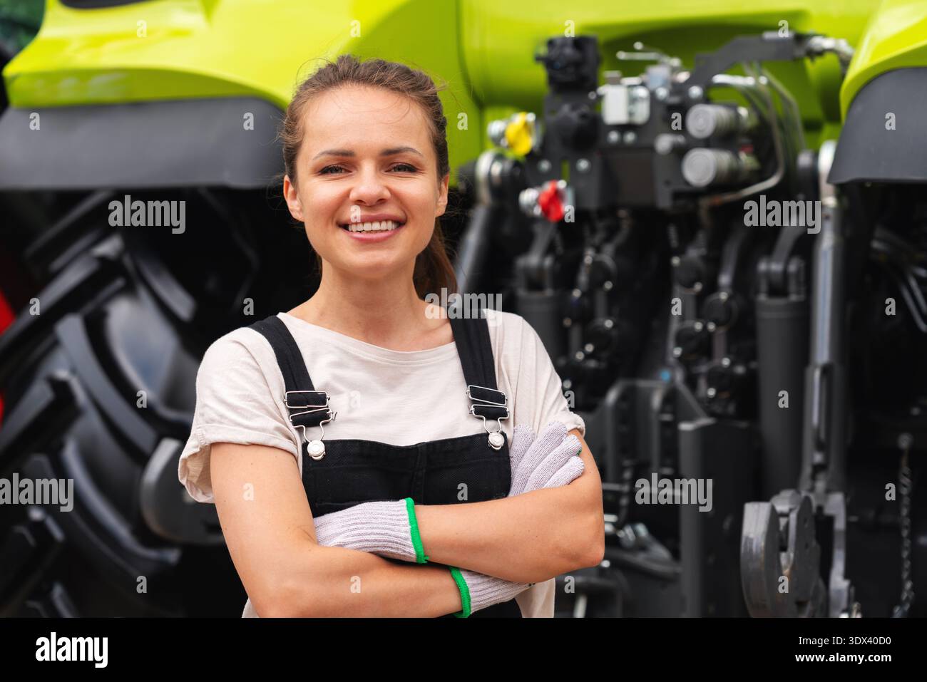 Porträt einer selbstbewussten Mechanikerin, die in der Nähe des Traktors steht Stockfoto