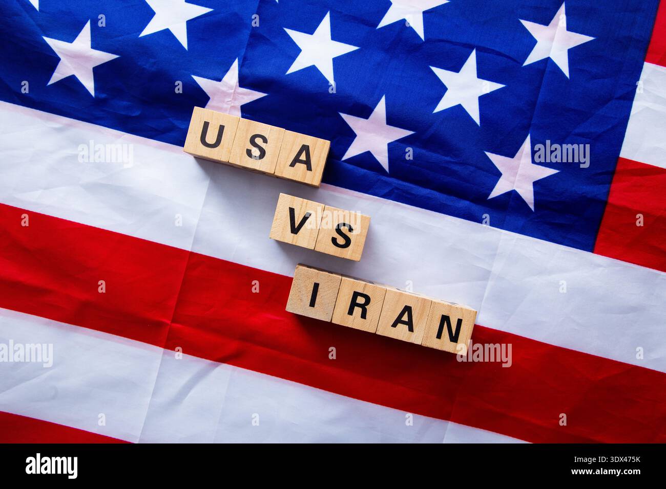 Die USA und der iran konfrontieren sich mit Holzblöcken auf einer US-Flagge, die den internationalen Konflikt symbolisieren Stockfoto