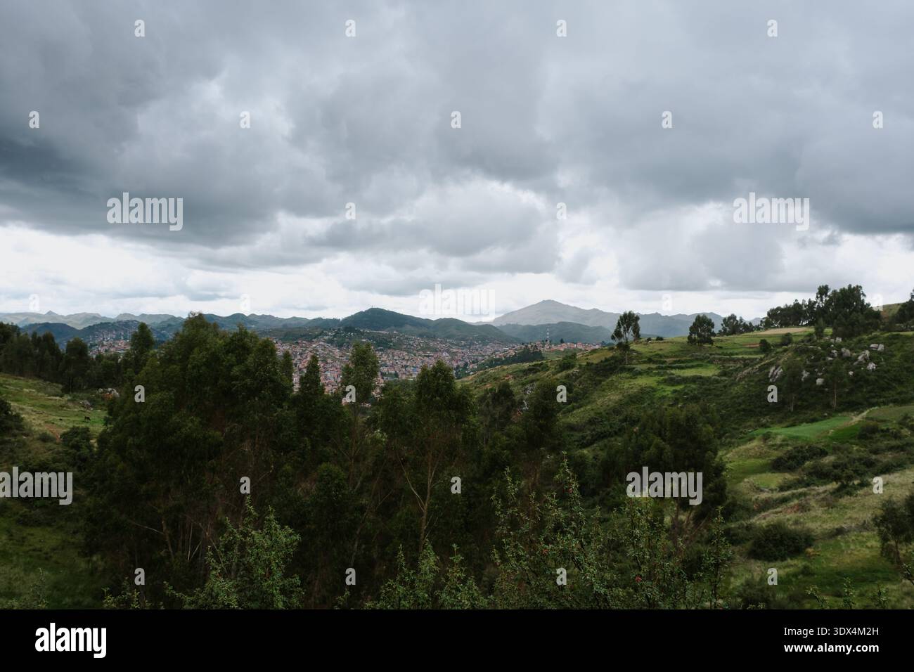 Malerische Landschaft der Stadt Cusco mit Bäumen im Vordergrund und den Anden im Hintergrund Stockfoto