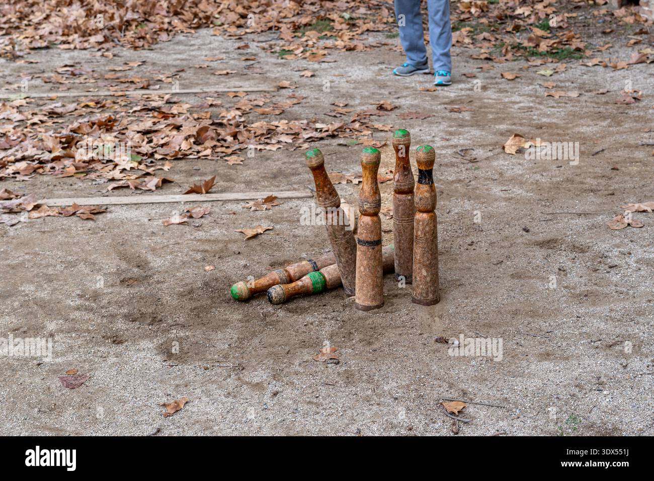 Hoher Winkel von traditionellen Holznadeln, die während eines Spiels von Bitlles auf eine unbefestigte Oberfläche fallen. Konzept: Handeln, Erfolg und Erreichen von Zielen. Stockfoto