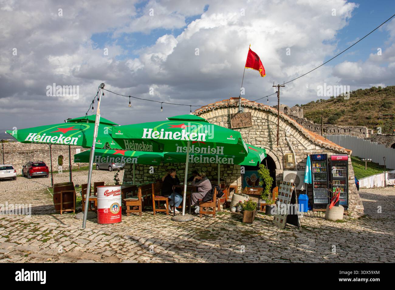 Kleines Café mit Sitzgelegenheiten im Freien und Sonnenschirmen im Schloss Berat in Berat, Albanien Stockfoto