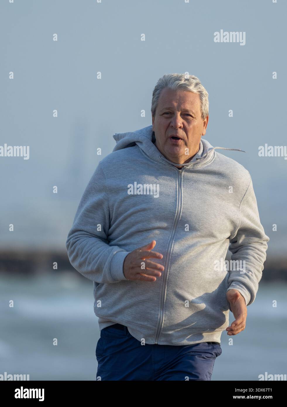 Senior-Mann joggt an der Küste entlang Stockfoto