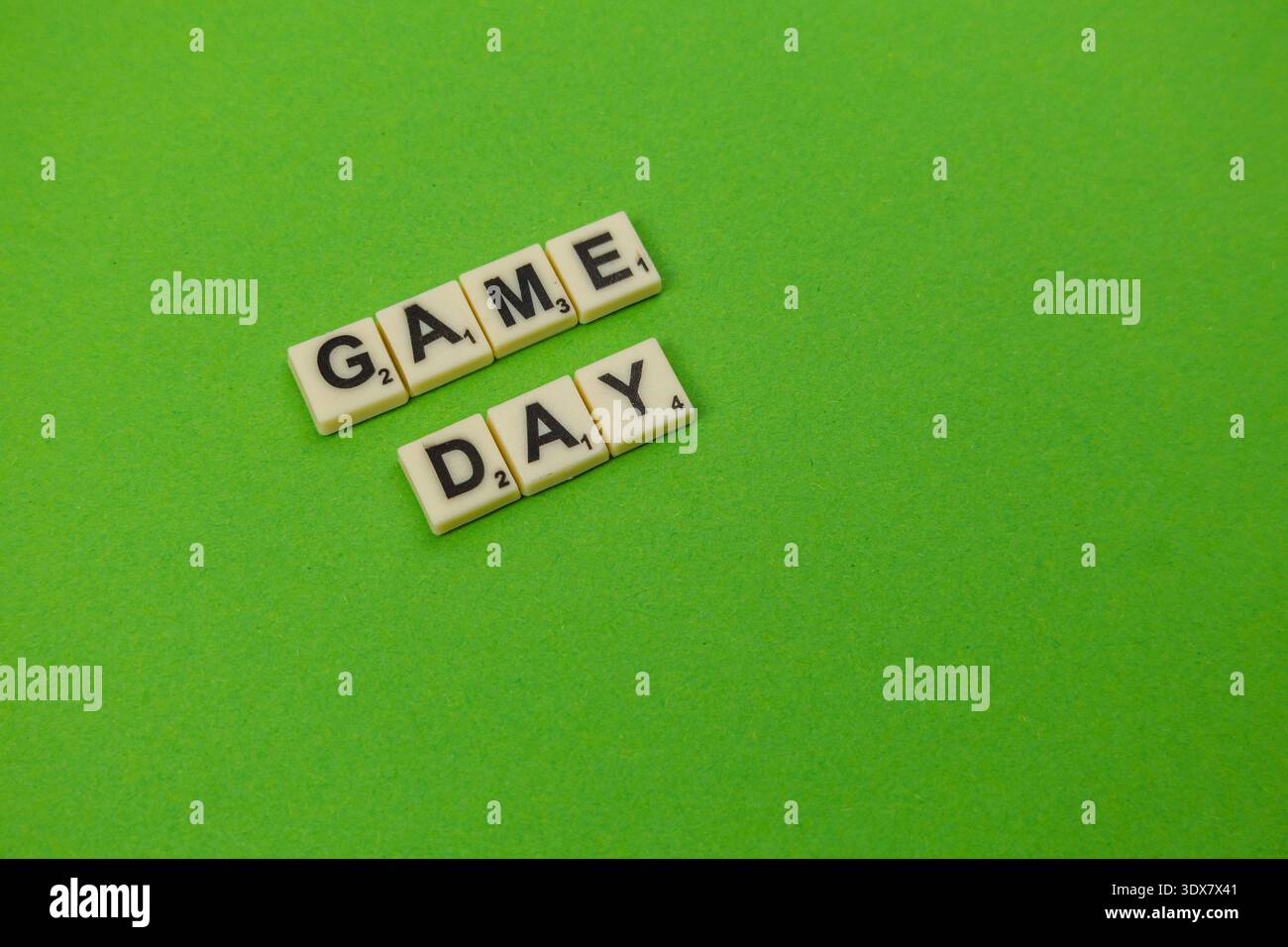 Am National Scrabble Day stehen hölzerne Buchstabenziegel auf einer hellgrünen Oberfläche für den Spieltag. Die Spieler genießen eine lustige Zeit, die sich auf Worte und Strategie konzentriert. Stockfoto