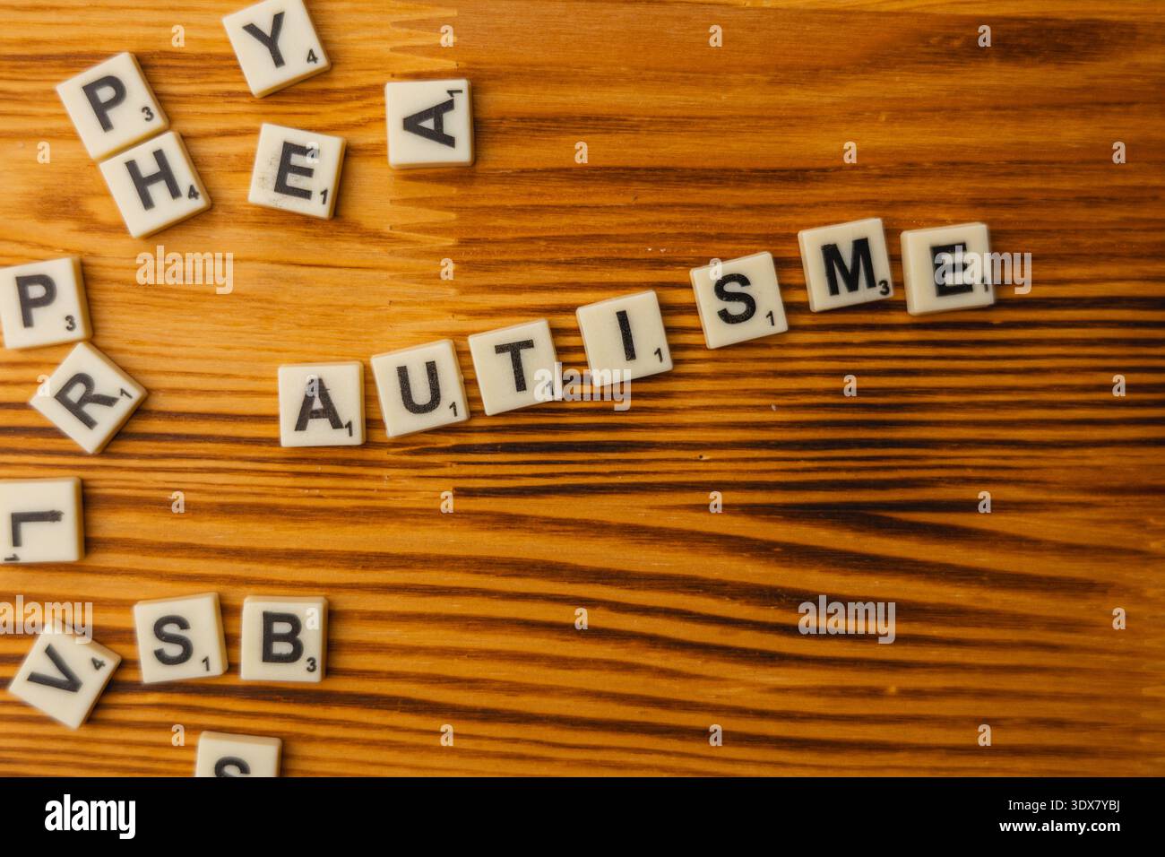 Am National Scrabble Day versammeln sich die Spieler an einem Holztisch, um das Wortspiel zu genießen. Die Buchstaben schreiben einzigartige Wörter aus, was Spaß und Lernspaß fördert Stockfoto