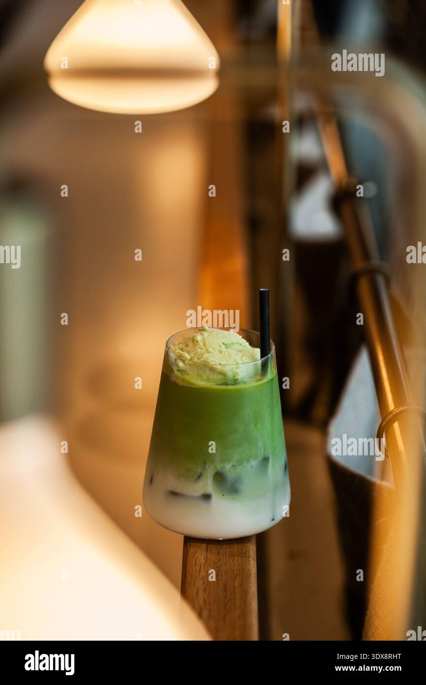 Ein erfrischender Matcha-Latte mit verschiedenen Lagen Milch und lebendigem grünem Tee, garniert mit einem reichhaltigen cremigen Schaum oder einer Portion Eis. Stockfoto