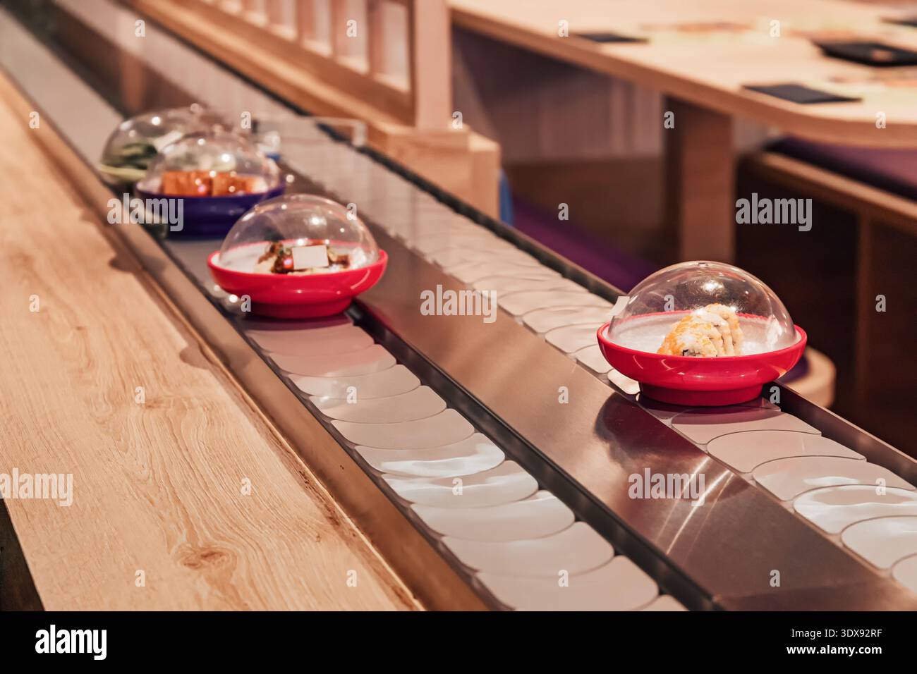 Sushi-Gerichte bewegen sich entlang eines Förderbandes in einem modernen japanischen Restaurant Stockfoto