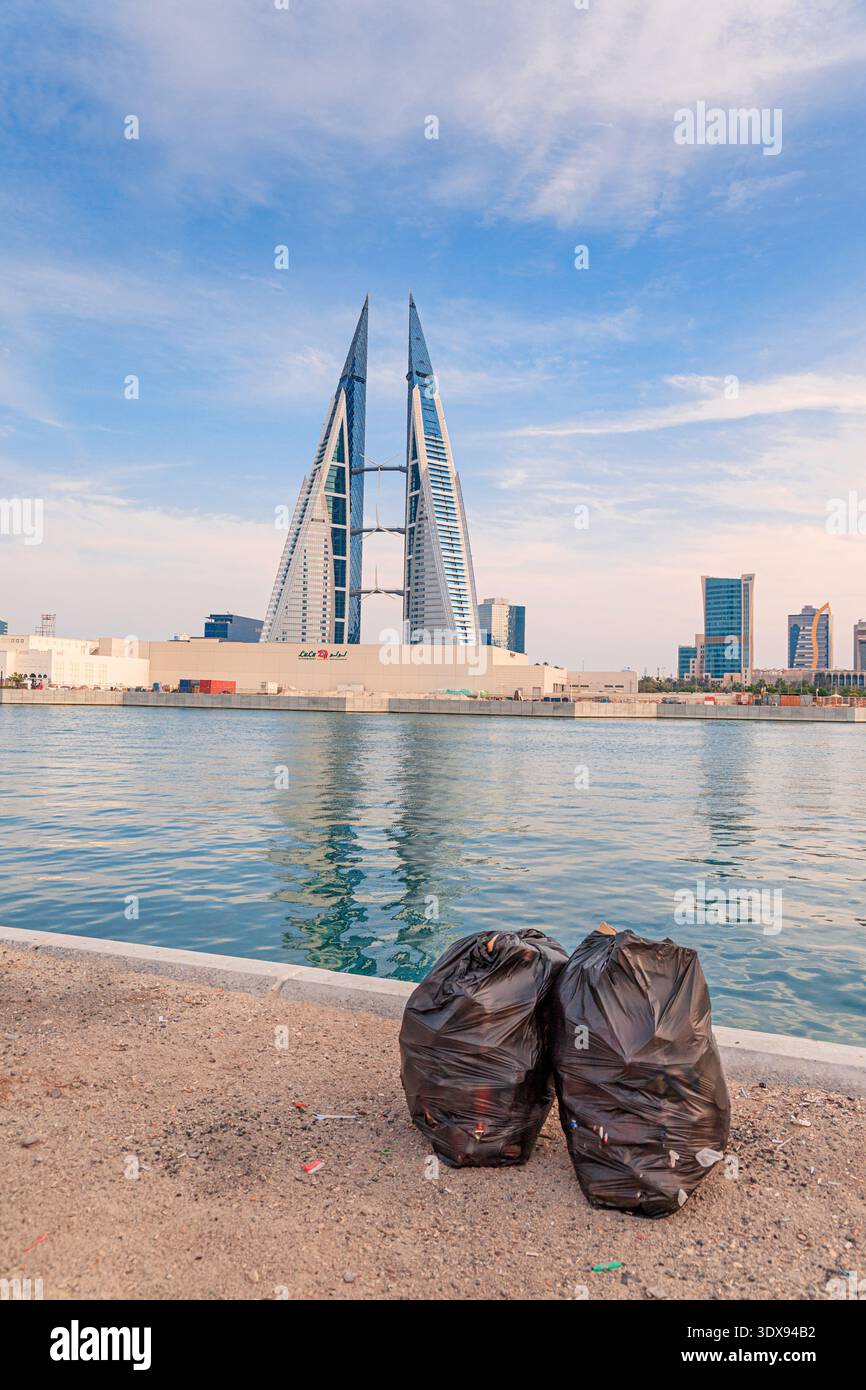 2. Dezember 2025, Bahrain, Manama: Zwei Müllsäcke stehen vor einer Skyline der Stadt und spiegeln städtische Abfälle und Umweltprobleme wider Stockfoto