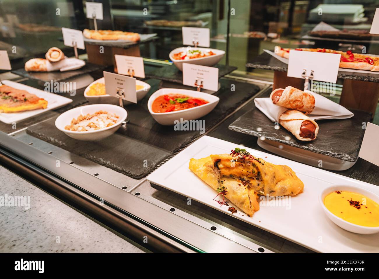 Verschiedene warme und kalte Gerichte werden hinter Glas in einem Selbstbedienungsbuffet serviert Stockfoto
