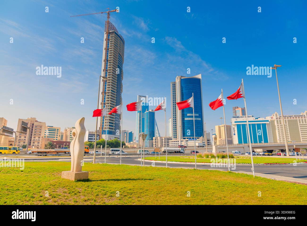 3. Dezember 2025, Bahrain, Manama: Skyline der Stadt mit modernen Hochhäusern, Nationalflaggen und einer zeitgenössischen Skulptur Stockfoto