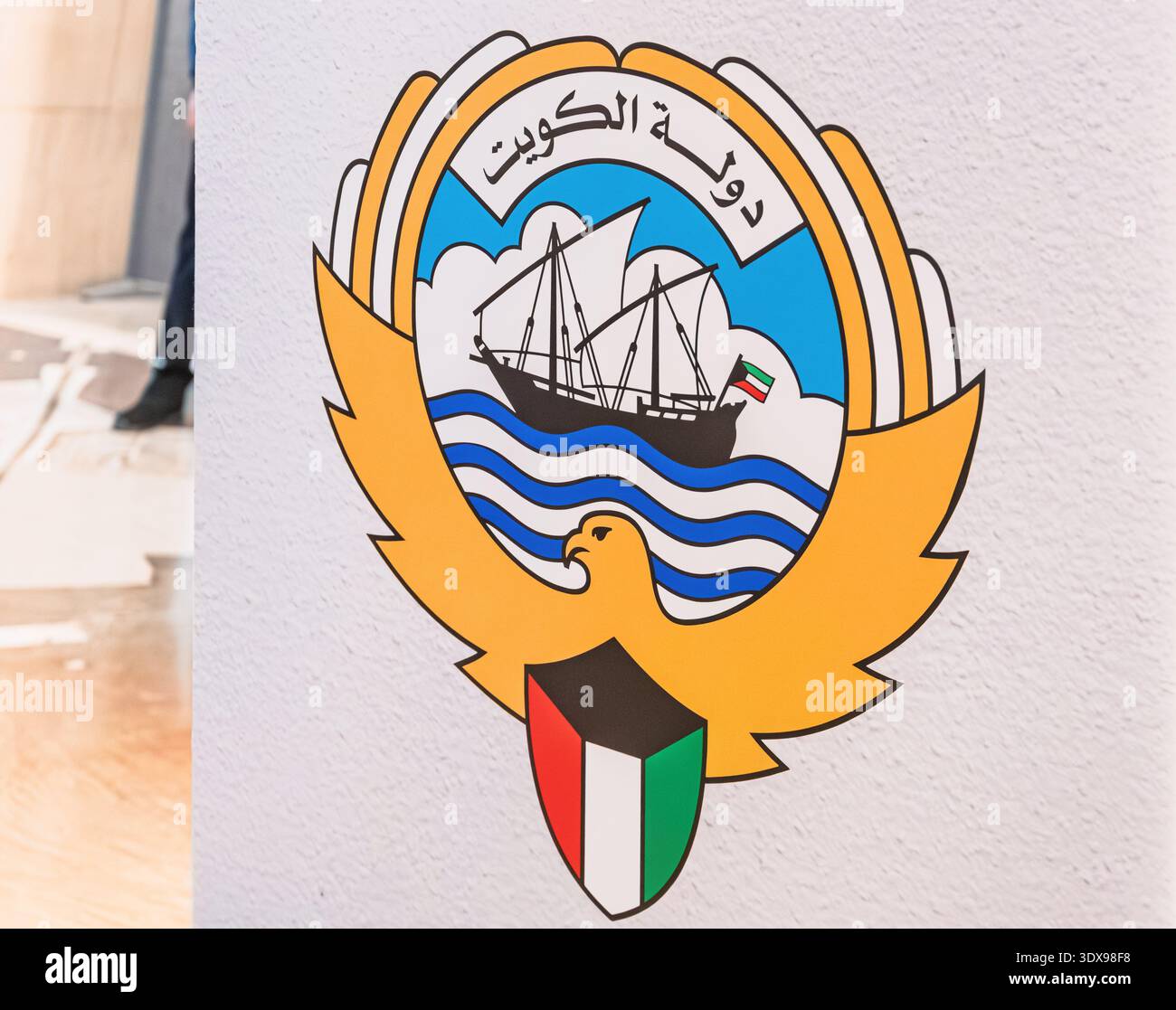 3. Dezember 2025, Bahrain, Manama, Nationalmuseum: Kuwait National Emblem mit einer Dau, die auf Wellen mit der Flagge, dem Falken und dem Schild segelt Stockfoto