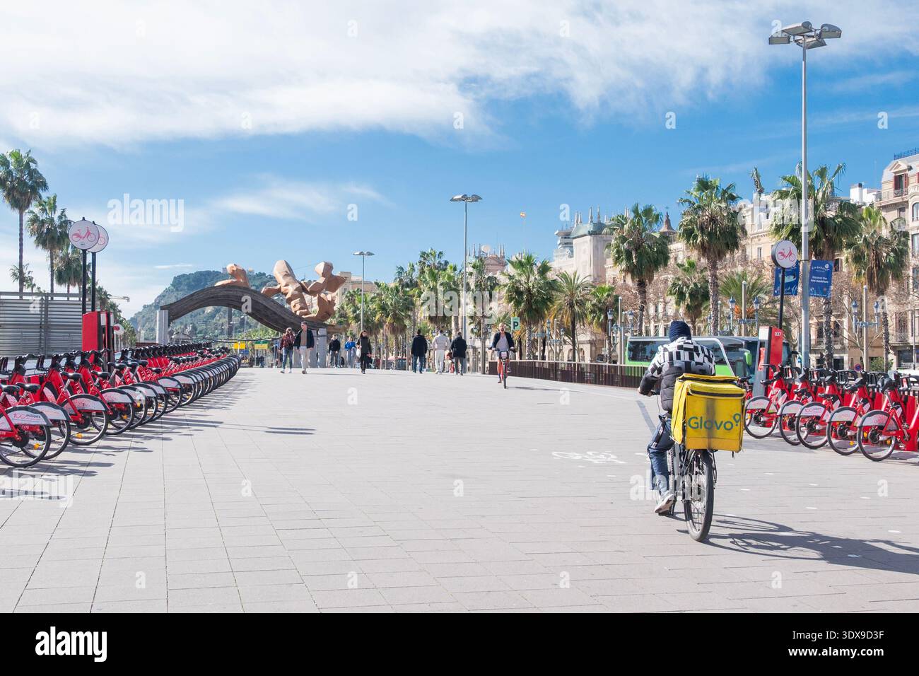 Barcelona Spanien, 19. Februar 2026 , Glovo Lieferfahrer radelt an einer Fahrradstation in Barcelona vorbei. Moderner urbaner Lebensstil, nachhaltige Stadt Stockfoto