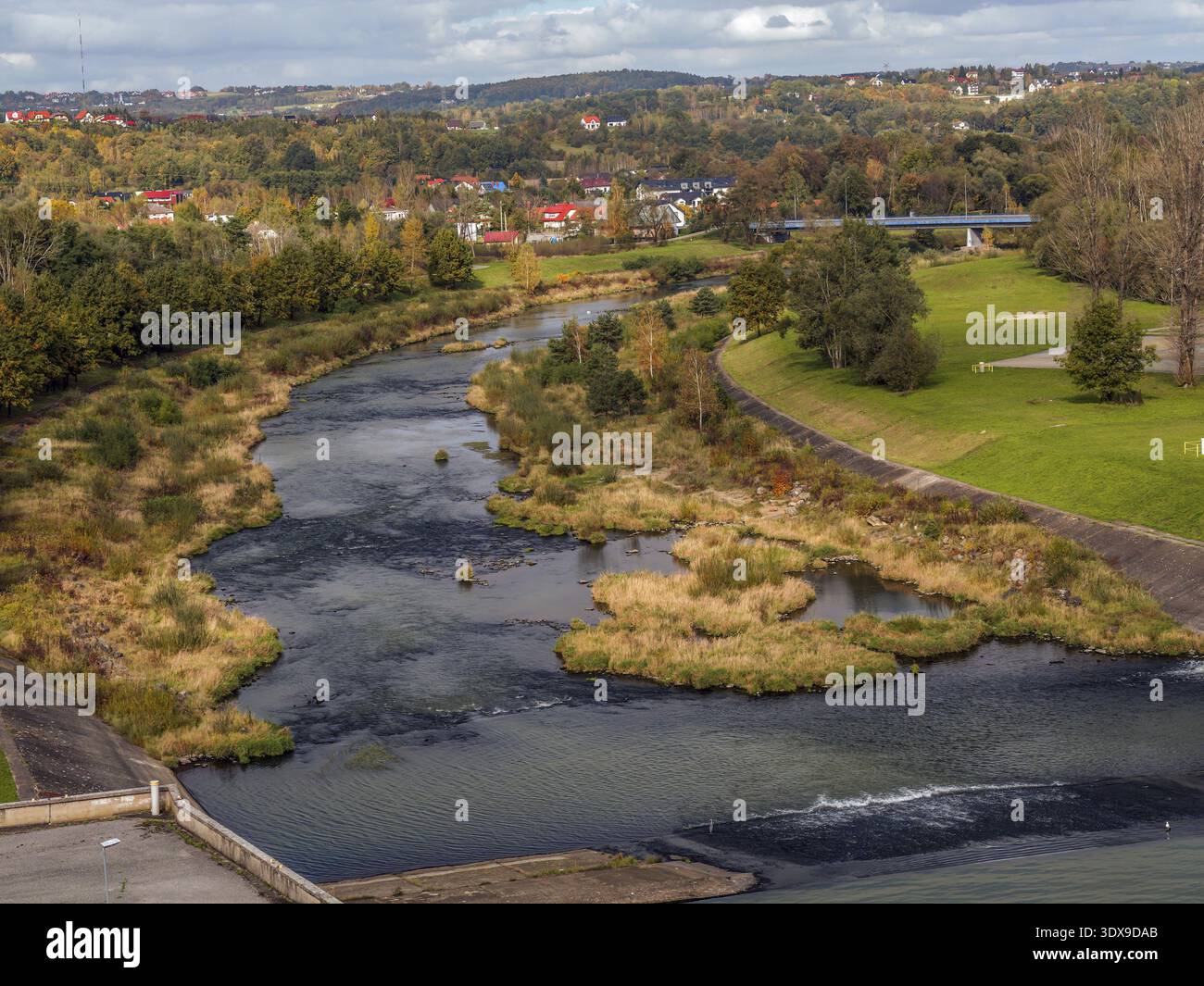 Ein malerischer Fluss schlängelt sich durch eine üppige Herbstlandschaft mit lebhaftem Laub und malerischen Häusern Stockfoto
