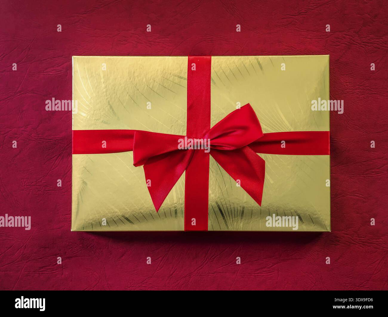 Goldene Schokoladenbox mit rotem Band von oben geschossen Stockfoto