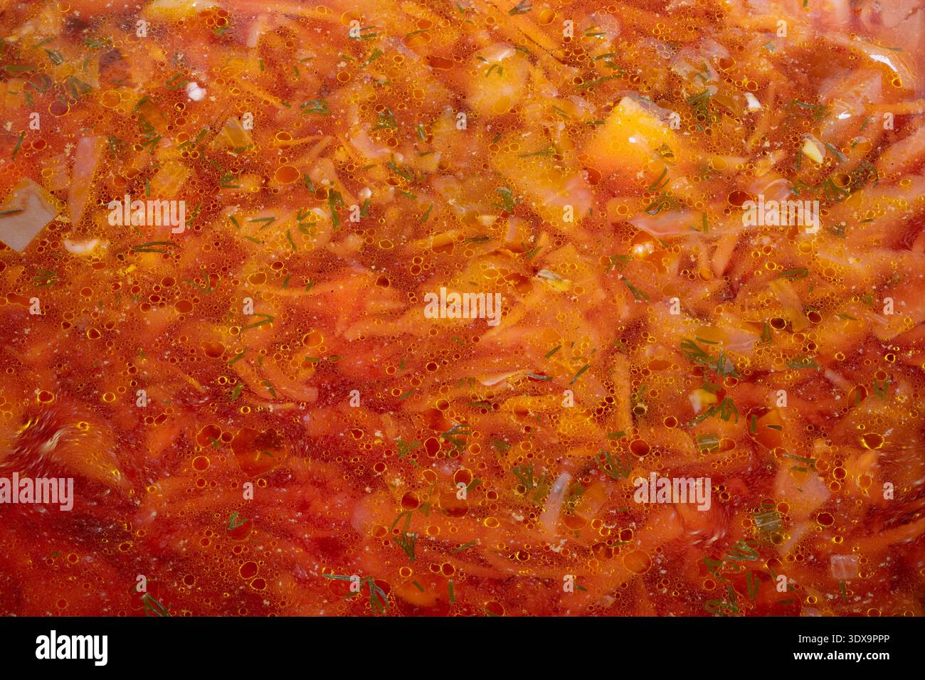 Hausgemachte Borschtsuppe duftend hellrot, langsam gekochter Kohl und Kartoffelstücke mit Zwiebeln und geriebener Rübe, rustikaler Holzlöffel, Zeugnis des Erbguts Stockfoto