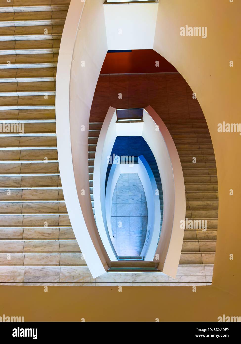 Symmetrischer Blick von oben auf moderne Wendeltreppe, geschwungene weiße Brüstungen und Marmortreppen, geometrische Linien, architektonischen Minimalismus. Stockfoto