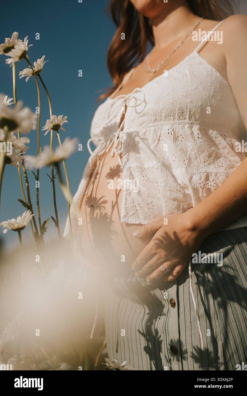 Mittelteil einer Frau, die inmitten von Blumen auf dem Feld steht Stockfoto