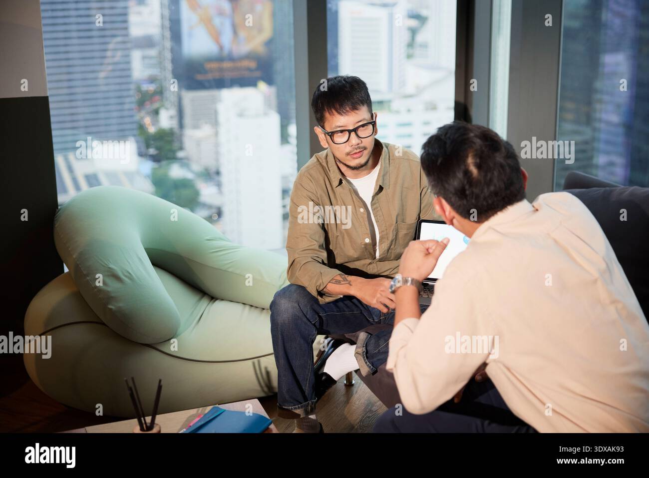 Hochwinkelansicht männlicher Unternehmer, die Strategien planen, während sie im Büro auf Sofa sitzen Stockfoto