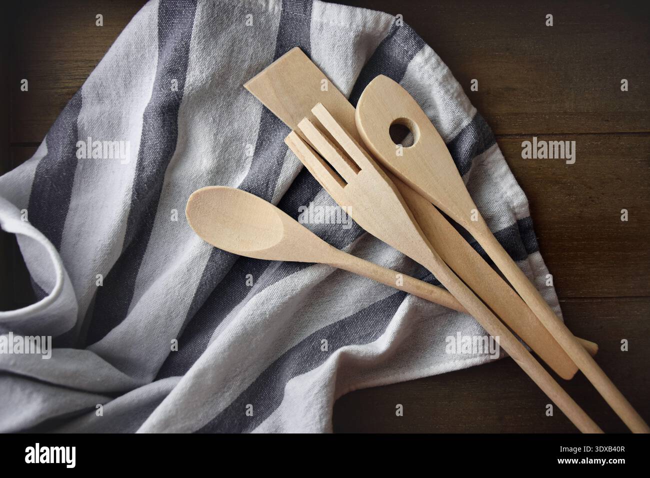 Küchenutensilien aus Holz auf grauem und weißem Baumwolltuch auf einem Holztisch Stockfoto