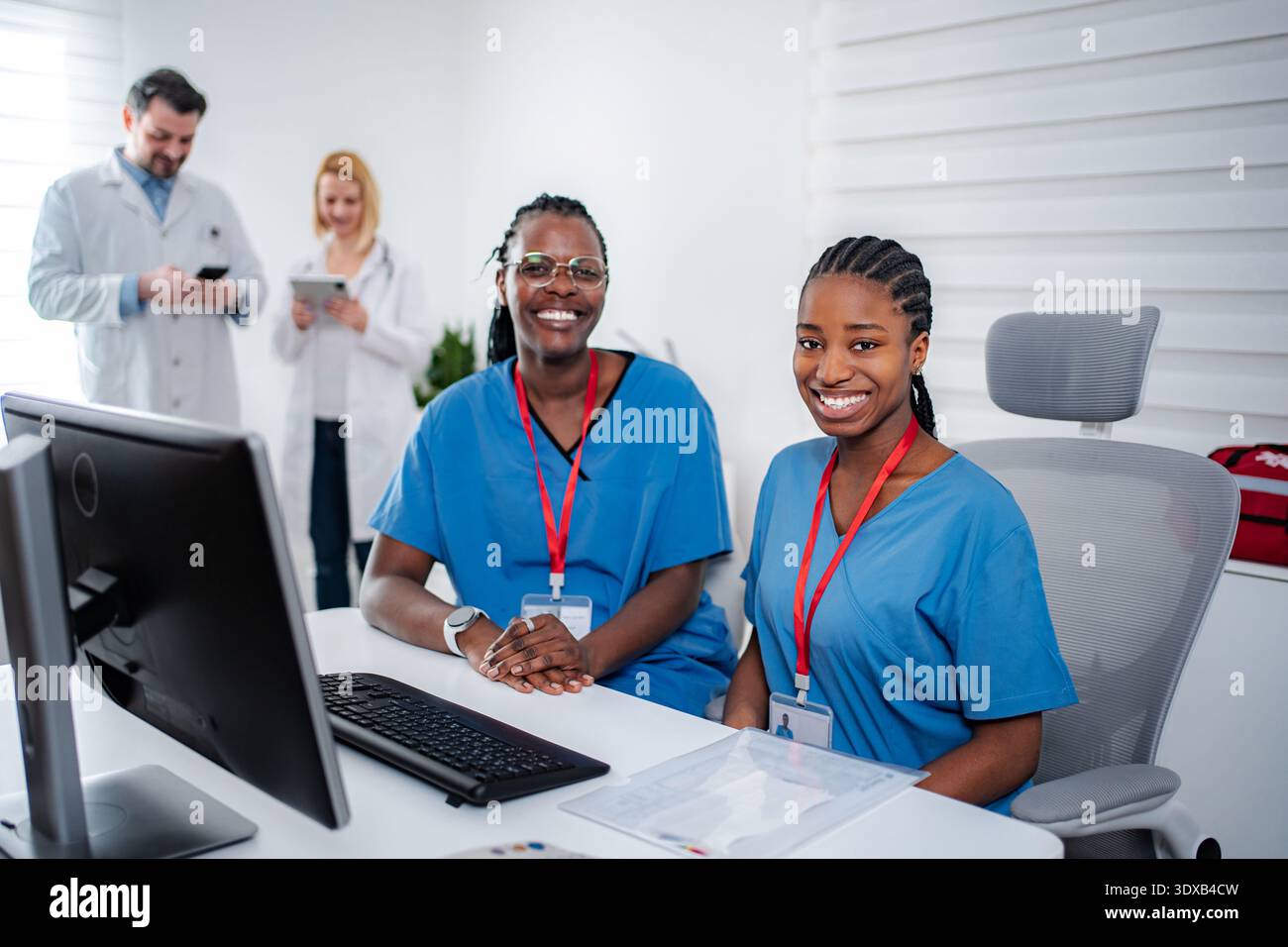 Glückliche weibliche medizinische Bewohnerinnen, die am Kliniktisch arbeiten Stockfoto