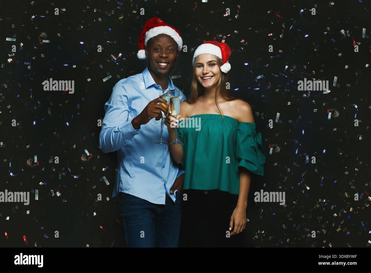 Fröhliche Feier mit Freunden, die Weihnachtsmützen tragen und während einer Feiertagsparty Getränke halten Stockfoto