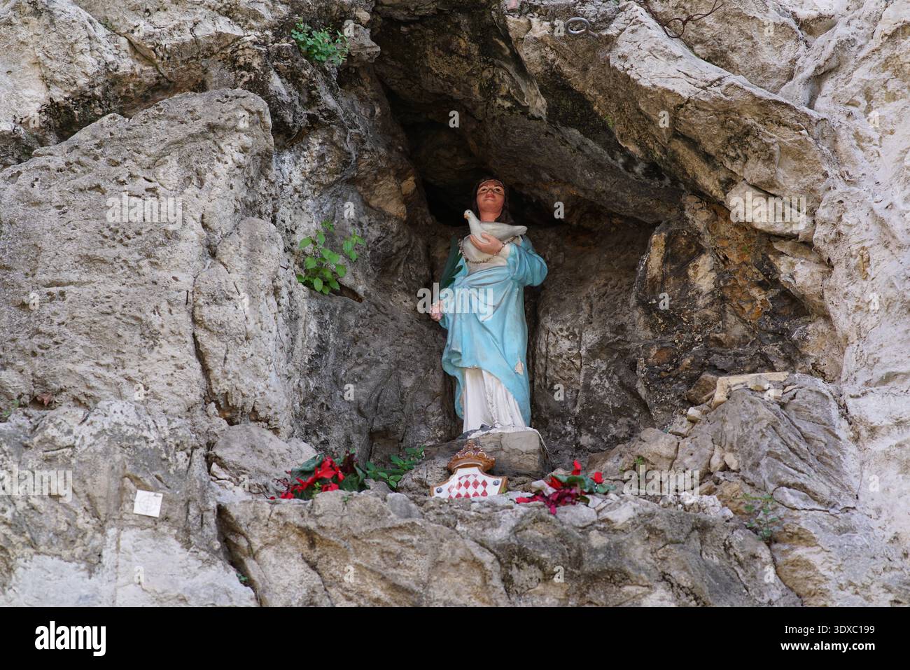 Statue von Sainte-devote in einer natürlichen Felsengrotte mit Blumen an der Basis in der Nähe der Chapelle Sainte-devote in Monaco.Monte Carlo, Monaco Stockfoto