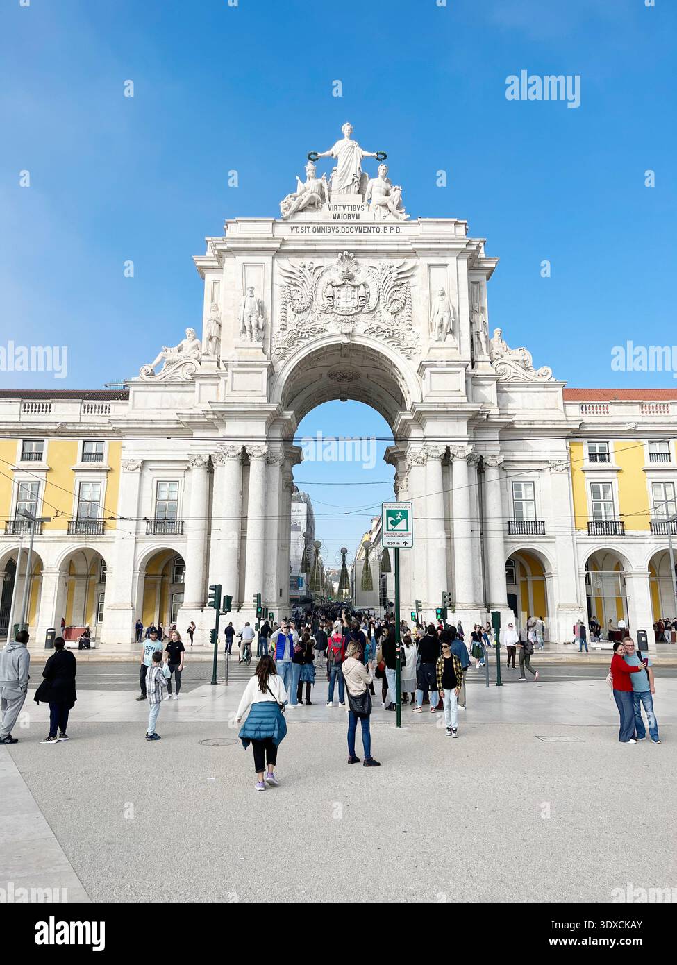 Touristen, die an einem sonnigen Tag unter dem Arco da Rua Augusta in Lissabon, Portugal, spazieren gehen. - Smartphone-aufgenommenes Stockfoto