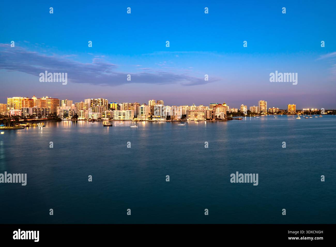 Die Skyline von Sarasota, Florida, leuchtet im goldenen Licht des Sonnenuntergangs über der Bucht. Stockfoto