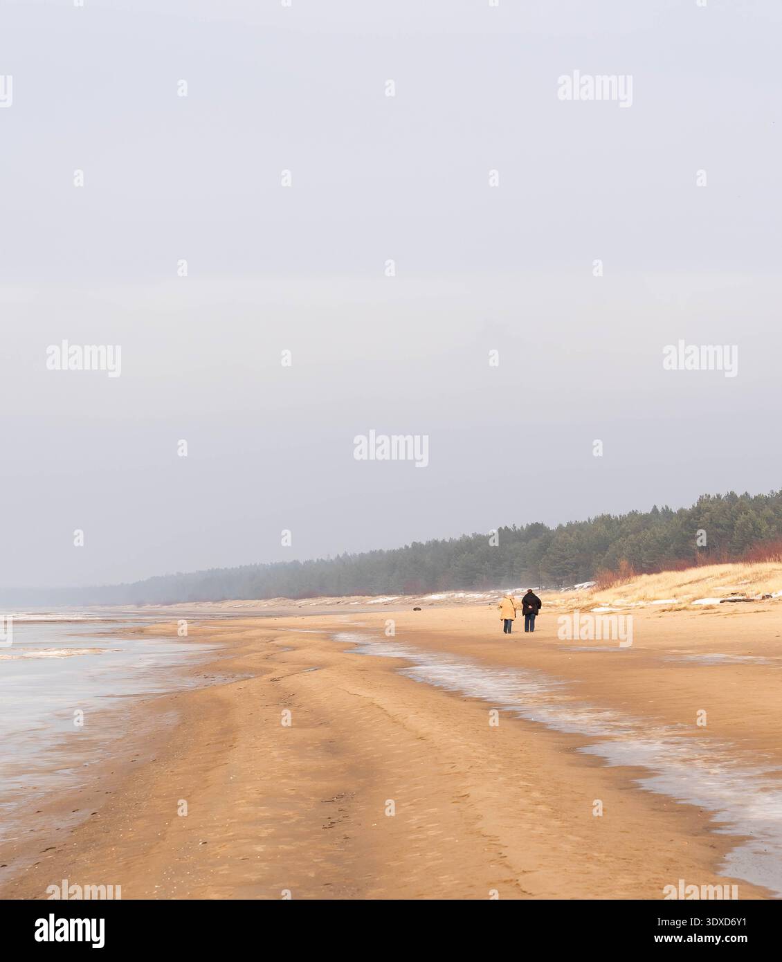 Menschen, die an einem breiten Sandstrand der Ostsee in Lilaste, Lettland, spazieren gehen Stockfoto