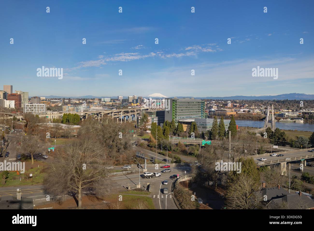 Stadtblick von Portland, Oregon mit Mount Adams im Hintergrund. Die Stadt ist voller hoher Gebäude, Brücken und Bäume. Autos fahren auf der Straße Stockfoto