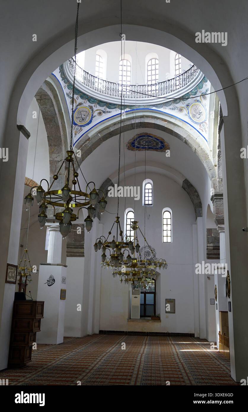 Große Kronleuchter hängen unter den gewölbten weißen Decken und der bemalten Kuppel des Innenraums einer historischen Moschee in Trabzon, Türkei Stockfoto